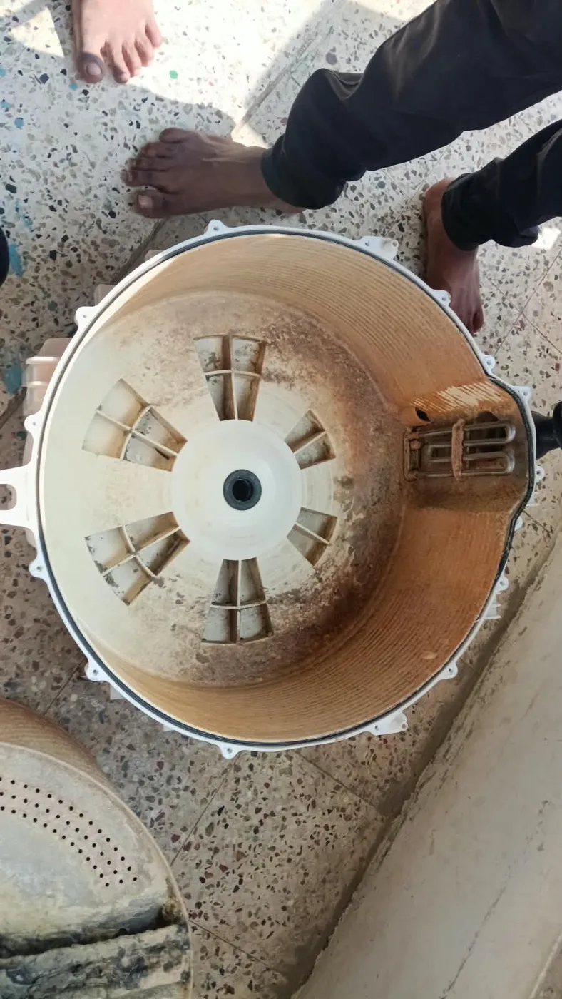 Technician cleaning a disassembled washing machine drum